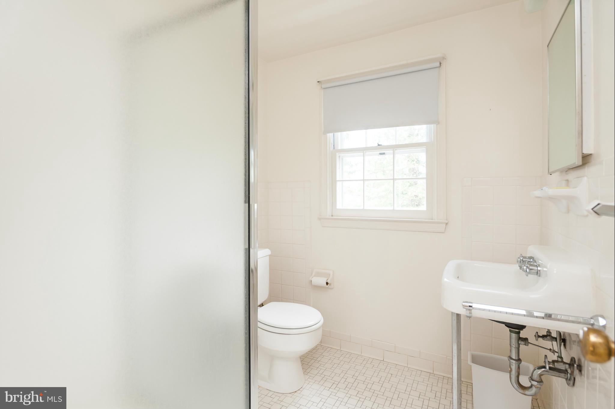 5918 Charlesmead Road Baltimore, MD 21212 - Photo 23 of 27 a bathroom with a toilet a sink a mirror and a window