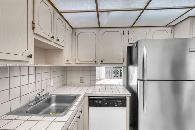 a kitchen with stainless steel appliances granite countertop a refrigerator a sink and white cabinets