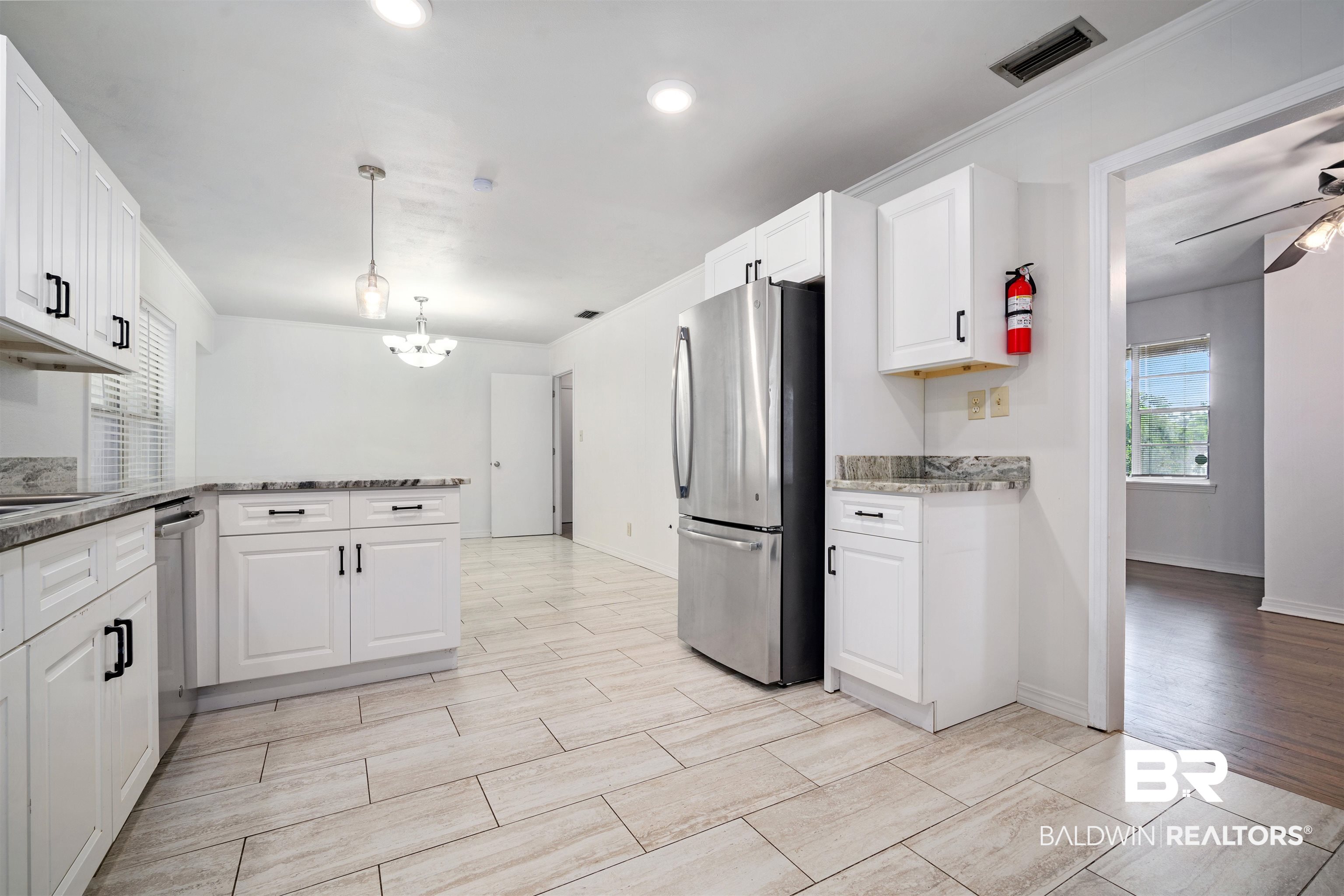 570 Markham Drive Mobile, AL 36609 - Photo 5 of 25 Kitchen with ceiling fan with notable chandelier, white cabinets, a peninsula, visible vents, and freestanding refrigerator