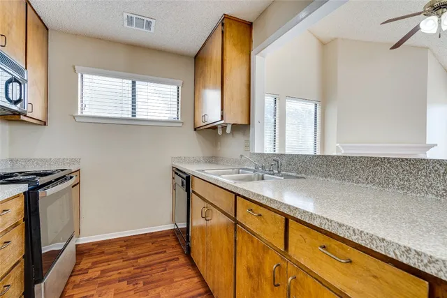 a kitchen with a sink a stove top oven and wooden floor
