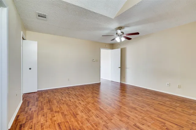 a view of empty room with wooden floor and fan