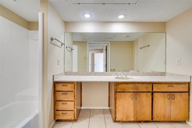 a bathroom with a granite countertop sink a mirror a bathtub and shower