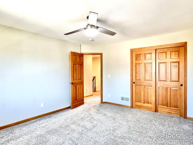 an empty room with closet area and chandelier fan