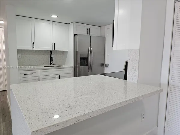 a large white kitchen with refrigerator stove and wooden cabinets