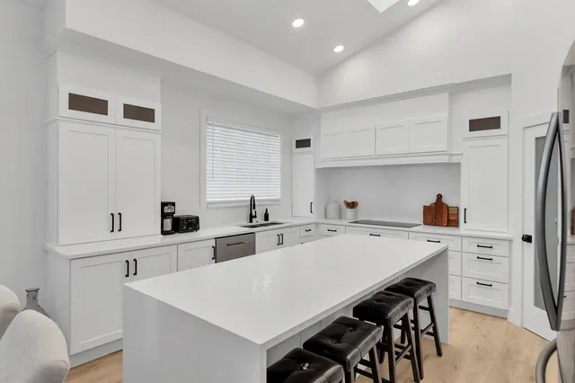 a kitchen with a sink a stove a refrigerator and white cabinets