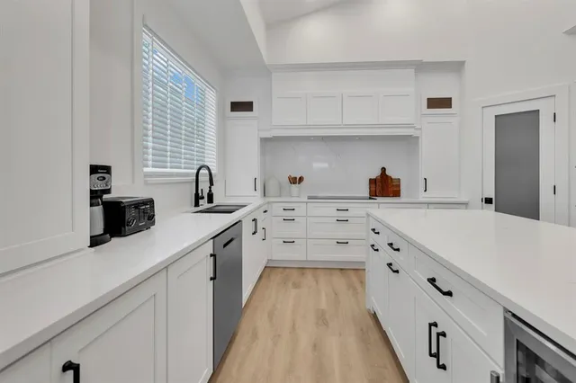 a kitchen with white cabinets sink and window