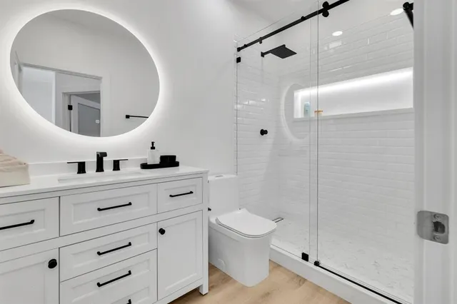 a bathroom with a double vanity sink a toilet a mirror and shower
