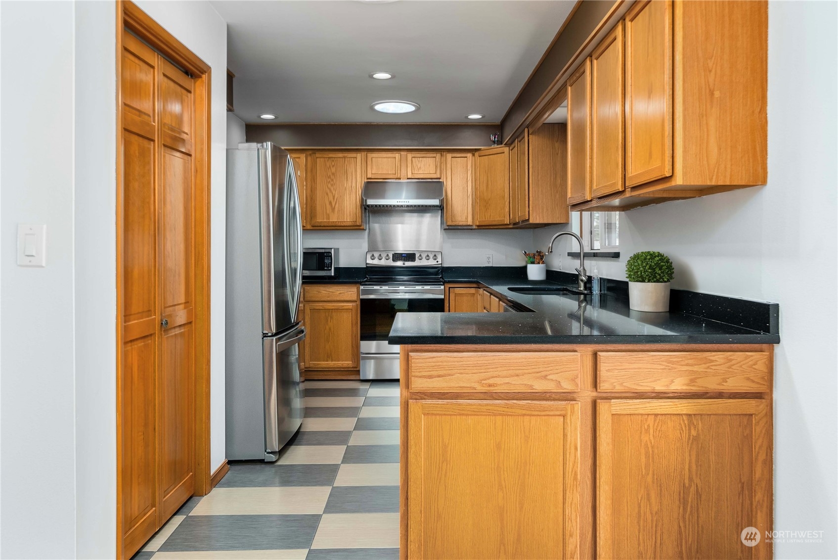 7211 Beverly Boulevard Everett, WA 98203 - Photo 9 of 36 a kitchen with stainless steel appliances granite countertop a refrigerator a sink dishwasher and wooden cabinets with wooden floor