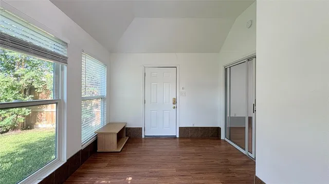 an empty room with windows and chandelier fan