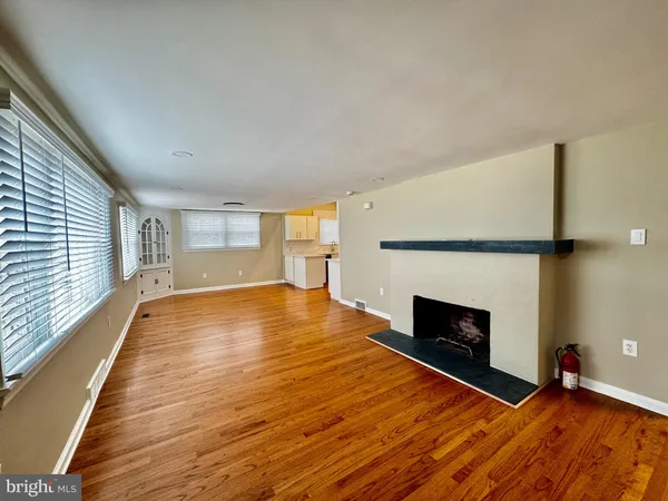 a view of empty room with wooden floor and fireplace