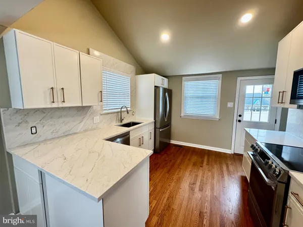a kitchen view with wooden floor sink stove and refrigerator