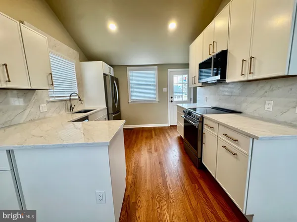 a kitchen with stainless steel appliances a sink dishwasher stove and microwave with wooden floor