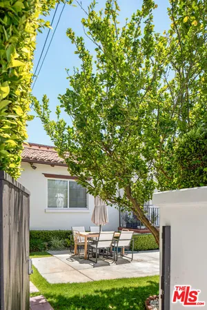 a view of a patio with table and chairs potted plants and large tree