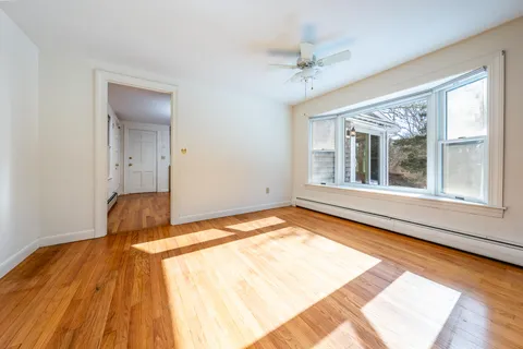 a view of an empty room with window and wooden floor