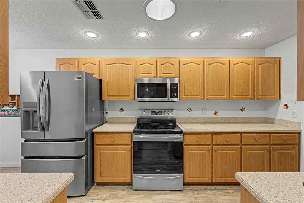 7406 Heather Walk Drive Weeki Wachee, FL 34613 - Photo 30 of 49 a kitchen with a refrigerator and a stove top oven