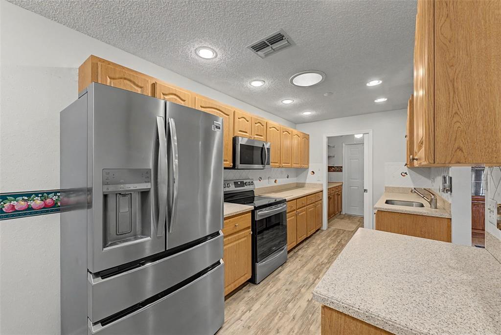 7406 Heather Walk Drive Weeki Wachee, FL 34613 - Photo 31 of 49 a large kitchen with stainless steel appliances granite countertop a refrigerator and a stove top oven