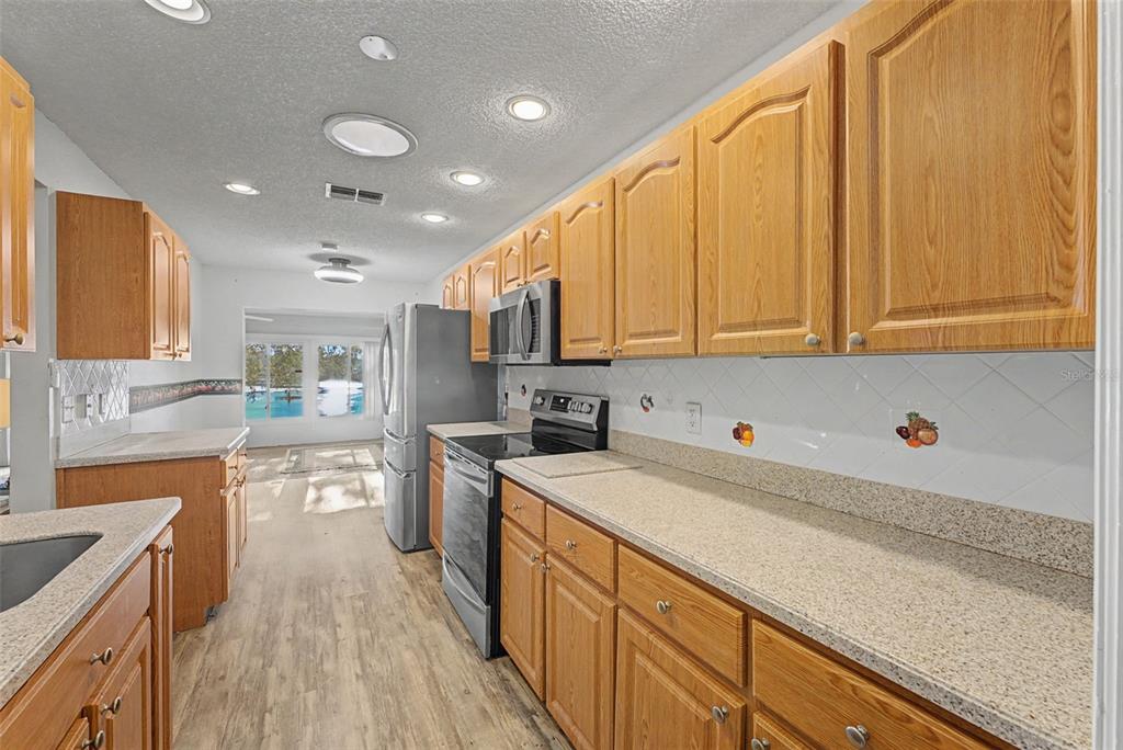 7406 Heather Walk Drive Weeki Wachee, FL 34613 - Photo 35 of 49 a kitchen with stainless steel appliances granite countertop a sink stove and refrigerator