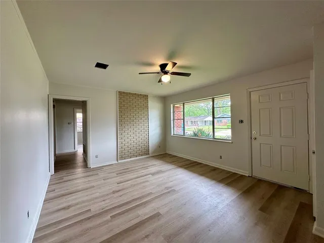 a view of an empty room with window and wooden floor