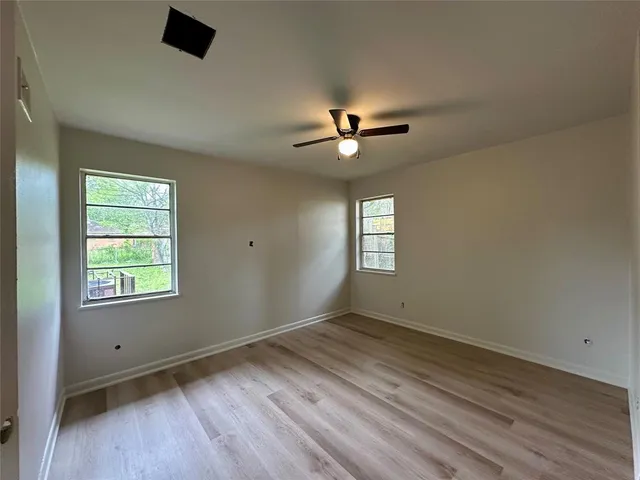 a view of empty room with wooden floor and fan