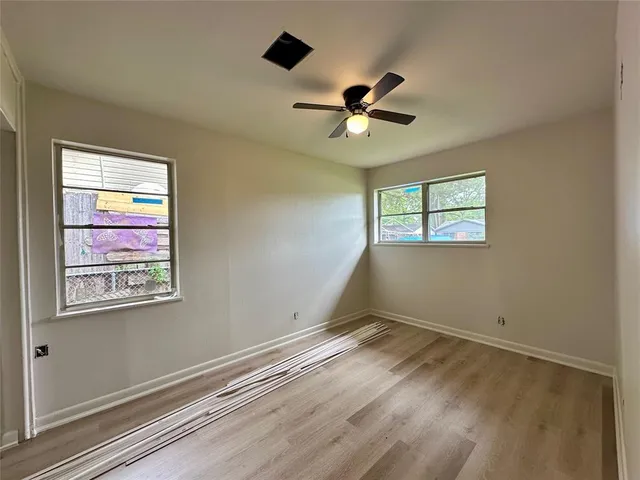 a view of empty room with wooden floor and fan