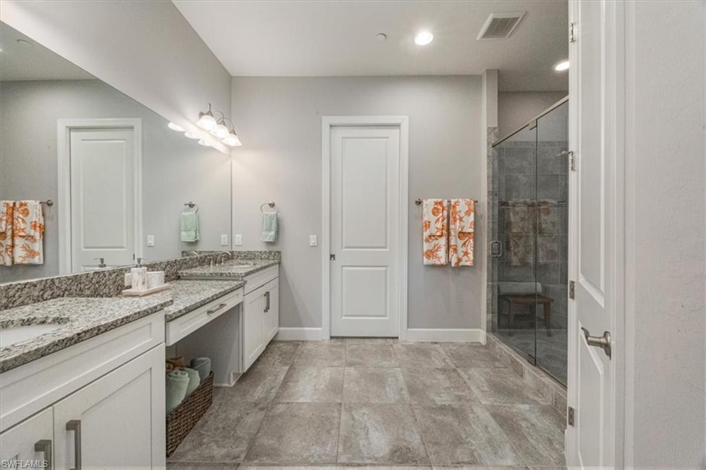 8773 Bellano Court, Unit 201 Naples, FL 34119 - Photo 18 of 34 a spacious bathroom with a granite countertop sink a mirror and a shower