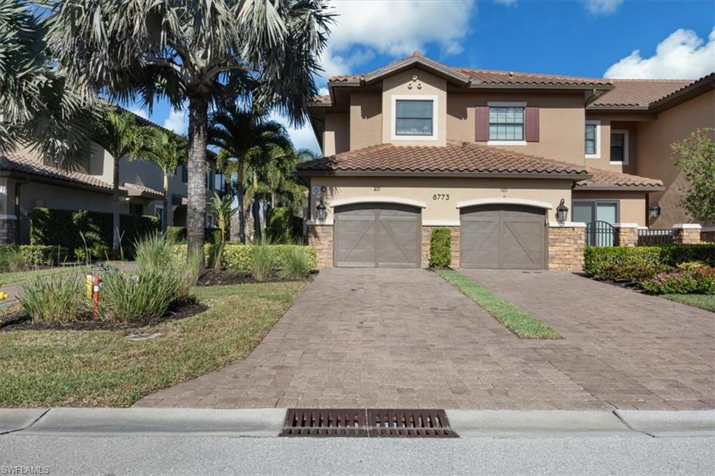 8773 Bellano Court, Unit 201 Naples, FL 34119 - Photo 2 of 34 a front view of a house with a yard and garage