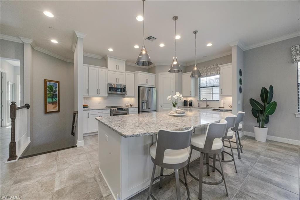 8773 Bellano Court, Unit 201 Naples, FL 34119 - Photo 7 of 34 a kitchen with stainless steel appliances kitchen island granite countertop a sink and cabinets