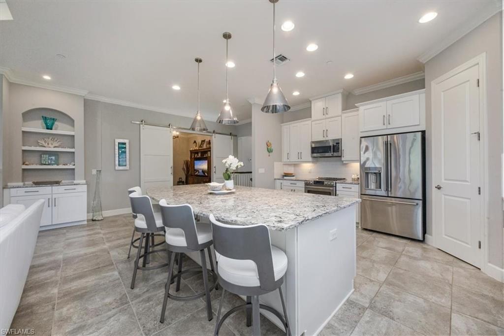 8773 Bellano Court, Unit 201 Naples, FL 34119 - Photo 8 of 34 a kitchen with stainless steel appliances granite countertop a table chairs and a refrigerator