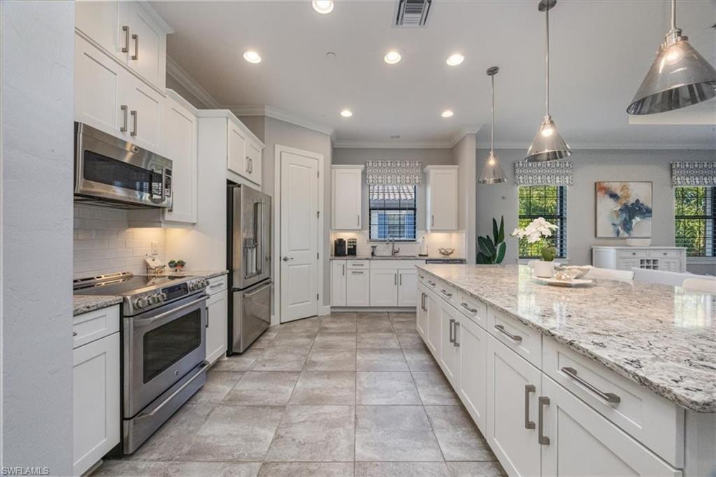 8773 Bellano Court, Unit 201 Naples, FL 34119 - Photo 9 of 34 a large kitchen with granite countertop a large kitchen island and a sink stainless steel appliances