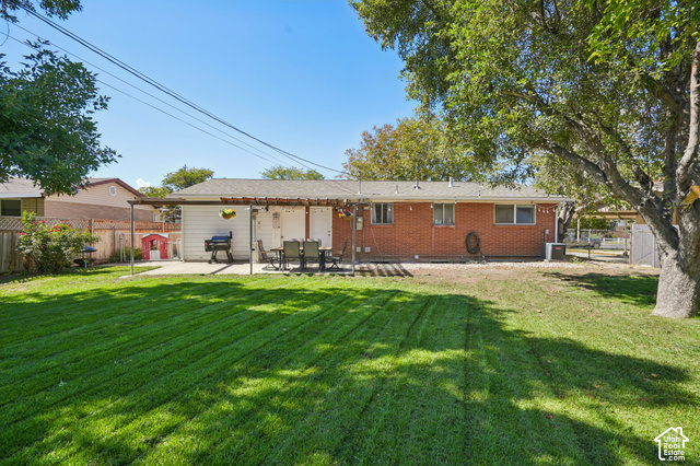 7391 Ramanee Drive Midvale, UT 84047 - Photo 36 of 45 Expansive grassy yard with a concrete patio featuring a pergola structure