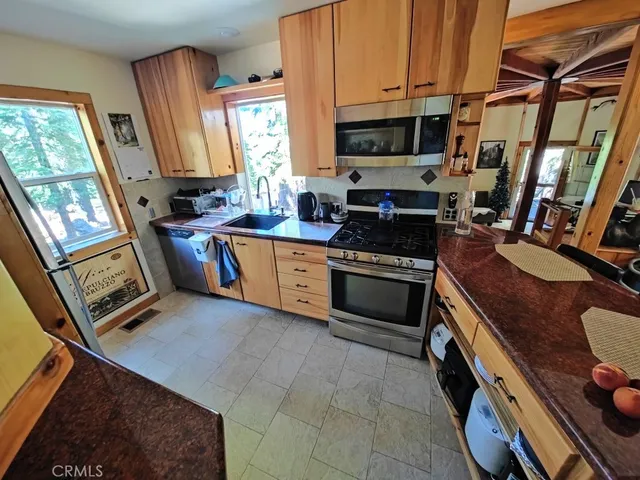 a kitchen with stainless steel appliances granite countertop a stove top oven a sink dishwasher and a fireplace