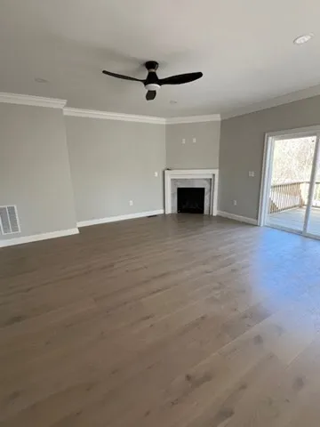 an empty room with wooden floor fireplace and windows