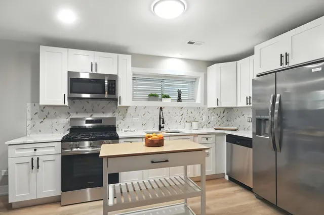 a kitchen with stainless steel appliances a stove a sink and a refrigerator