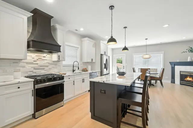 a kitchen with stainless steel appliances a stove a sink a oven a table and chairs