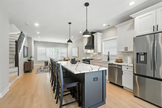 a kitchen with stainless steel appliances kitchen island a table chairs refrigerator and microwave