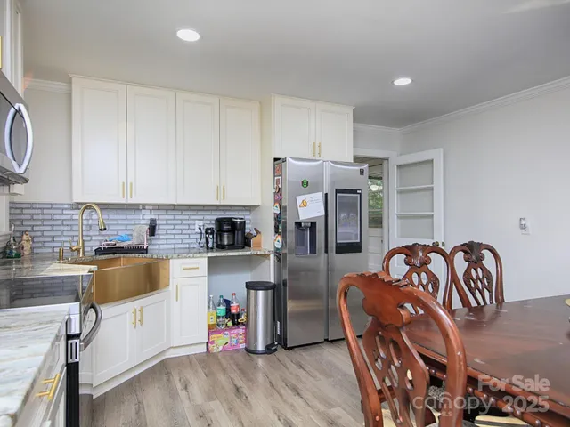 a kitchen that has a lot of white cabinets and stainless steel appliances