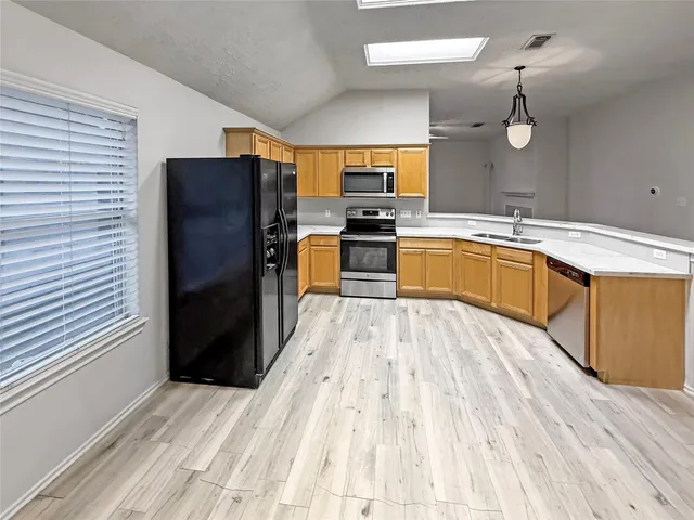 a large kitchen with a refrigerator and wooden floor