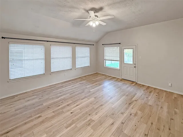 an empty room with wooden floor and windows
