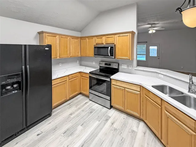 a kitchen with granite countertop a refrigerator stove top oven and sink