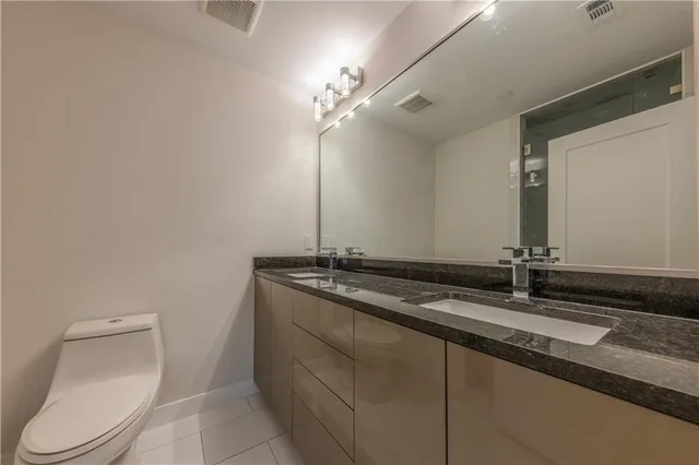 a bathroom with a granite countertop sink a toilet and a mirror