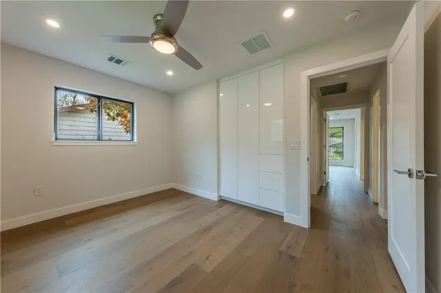 an empty room with wooden floor cabinet and windows