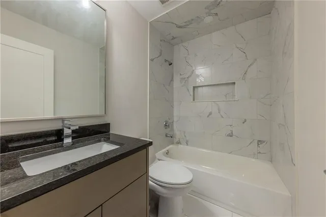 a bathroom with a granite countertop sink toilet and bathtub