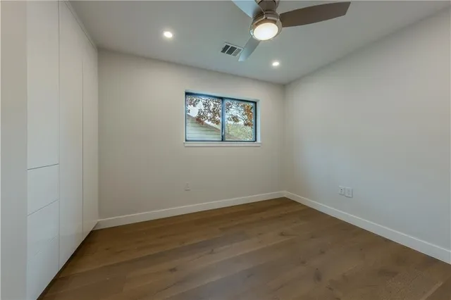 an empty room with a ceiling fan and window