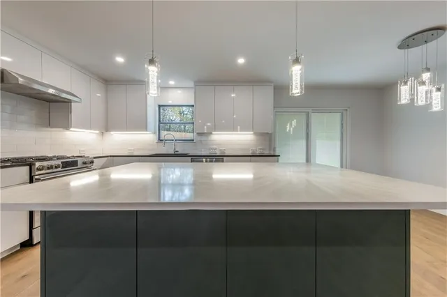 a view of kitchen with kitchen island a sink dishwasher a stove and a refrigerator with wooden floor
