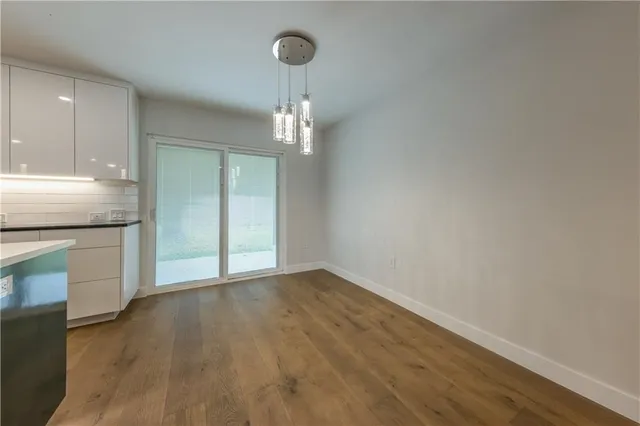 a view of an empty room with a kitchen and a window