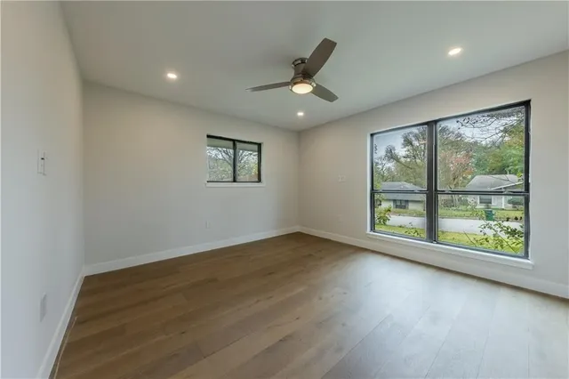 an empty room with wooden floor and windows