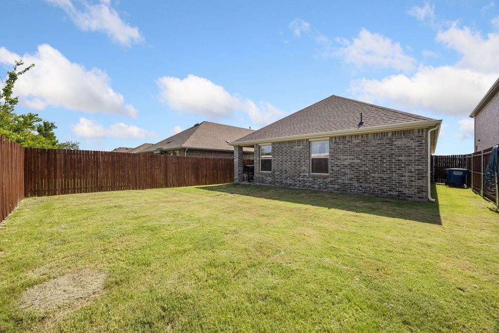 822 Ramble Road Lavon, TX 75166 - Photo 31 of 35 Expansive backyard featuring a manicured lawn, complete wood privacy fencing, and brick exterior