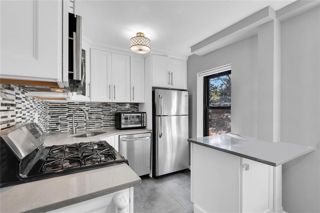 1265 Shore Parkway, Unit 2C Brooklyn, NY 11214 - Photo 5 of 11 a kitchen with white cabinets and appliances