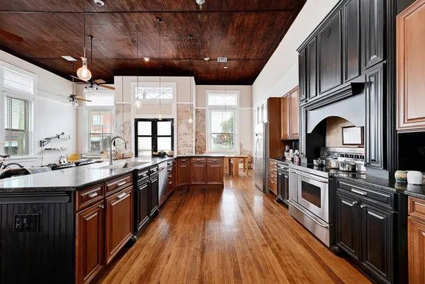 a kitchen with stainless steel appliances a stove a sink dishwasher a refrigerator and white cabinets with wooden floor