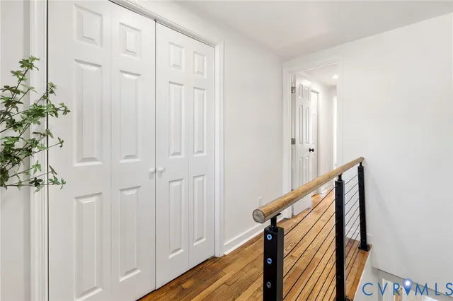 a view of a hallway with wooden floor and staircase
